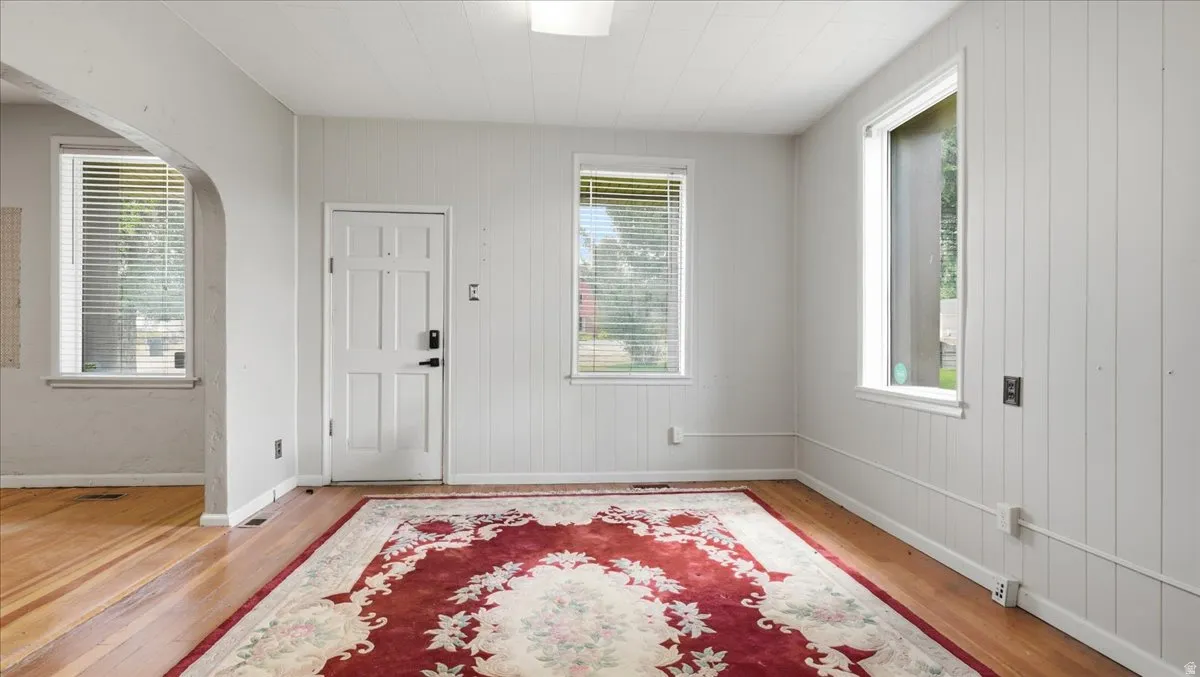 Interior space featuring wood-finish flooring, white paneling, and an arched doorway