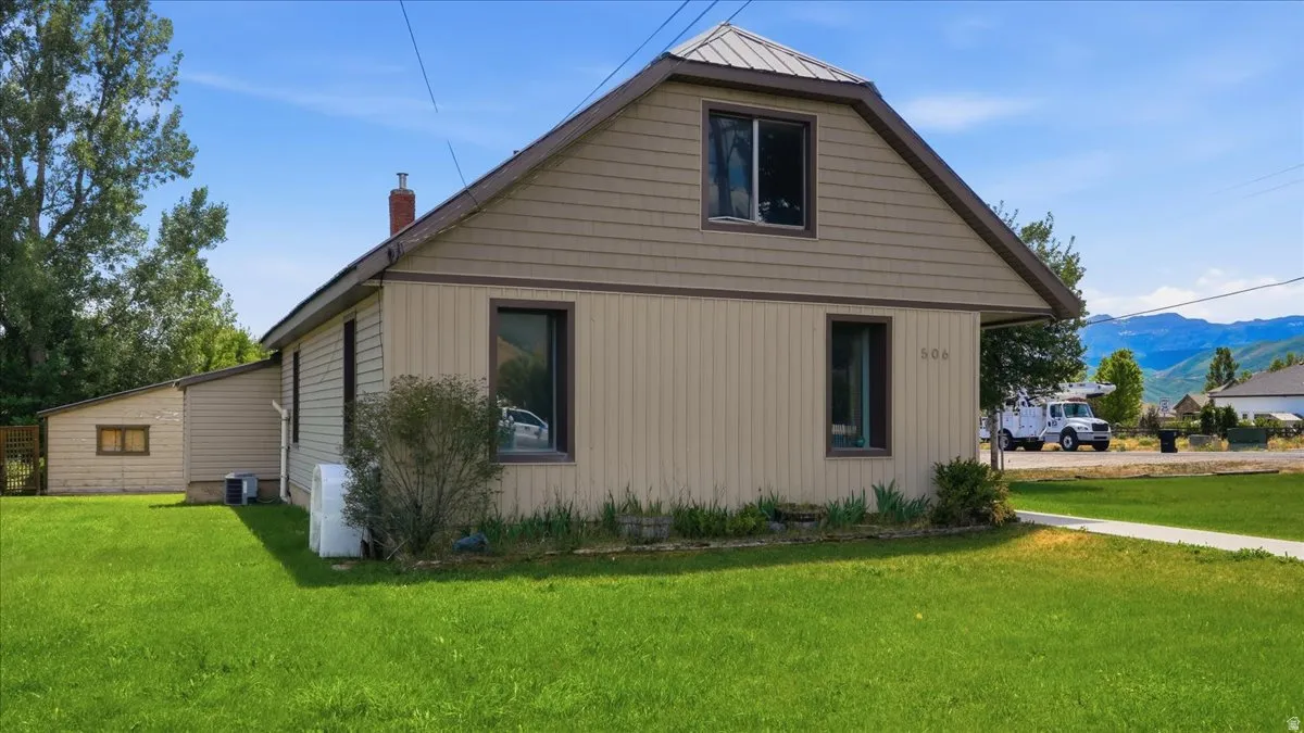 Property exterior featuring two-tone siding, a gable roof with metal covering, and a detached structure