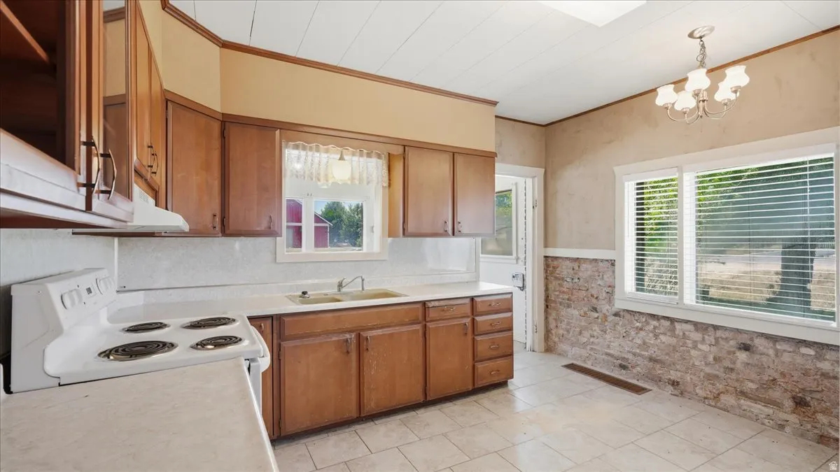 Kitchen featuring wood cabinetry, a double basin sink, and a white electric range