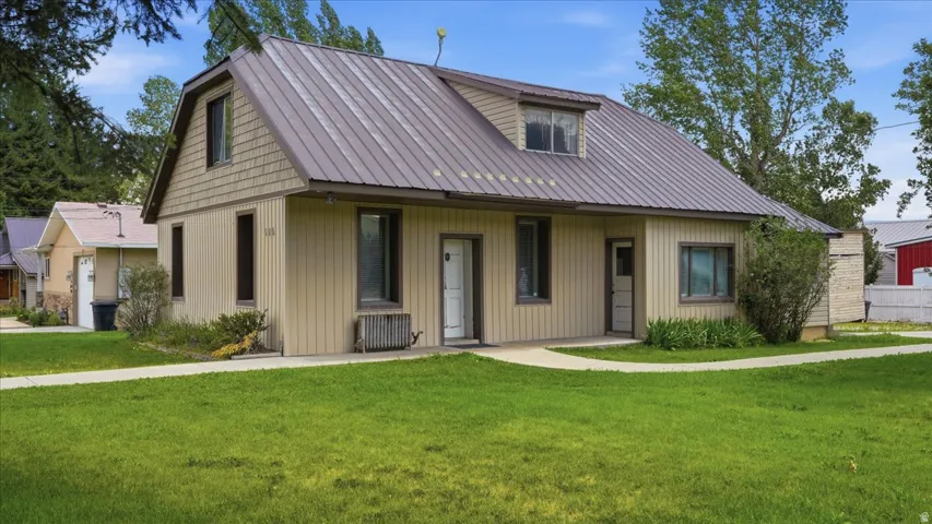 Two-story residence featuring a metal roof, dormer windows, vertical siding, and shake siding accents