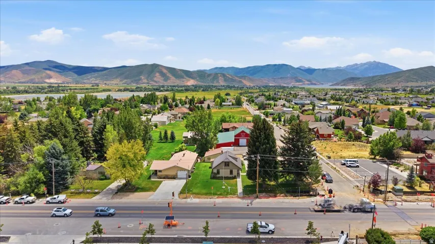 Aerial perspective showcasing a residential neighborhood with varied architectural styles, mature landscaping, and mountain backdrops