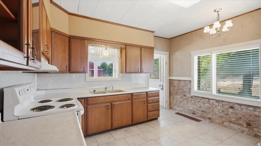 Kitchen featuring wood cabinetry, a double basin sink, and a white electric range