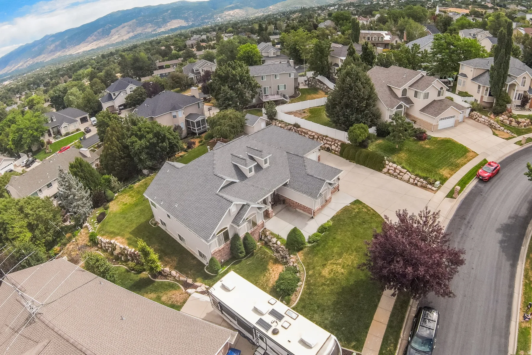 Contemporary home featuring a multi-gabled roof, stone and siding exterior, two-car garage, and mature landscaping