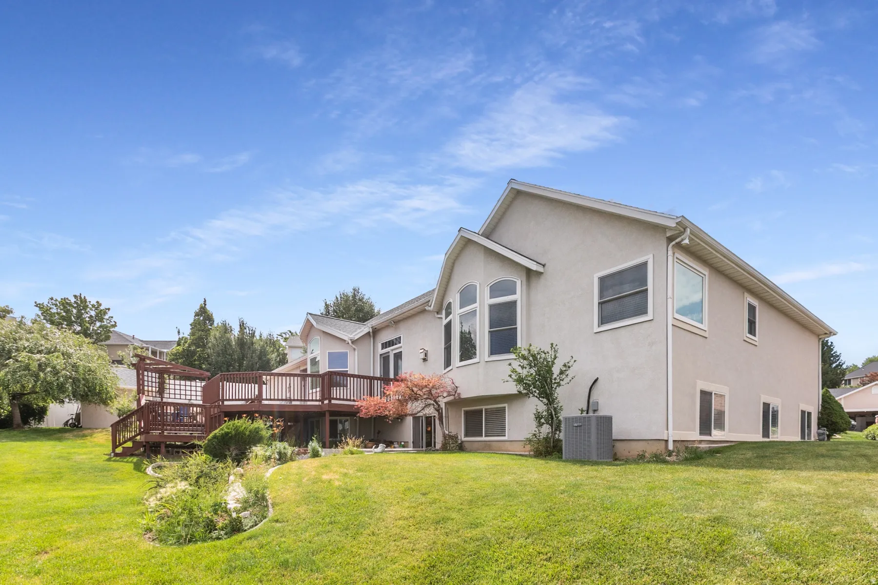 Expansive backyard featuring a multi-level wood deck, mature landscaping, and a manicured lawn