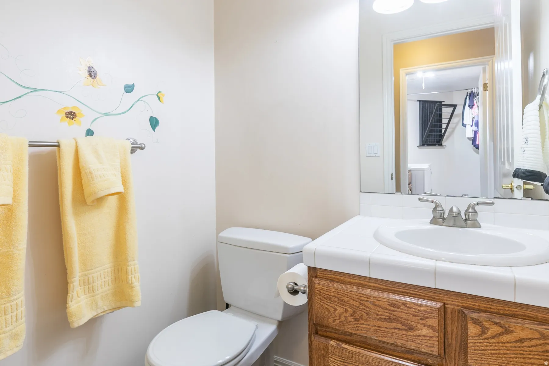 Bathroom vanity featuring a tile countertop with an integrated sink and a wood-finish cabinet