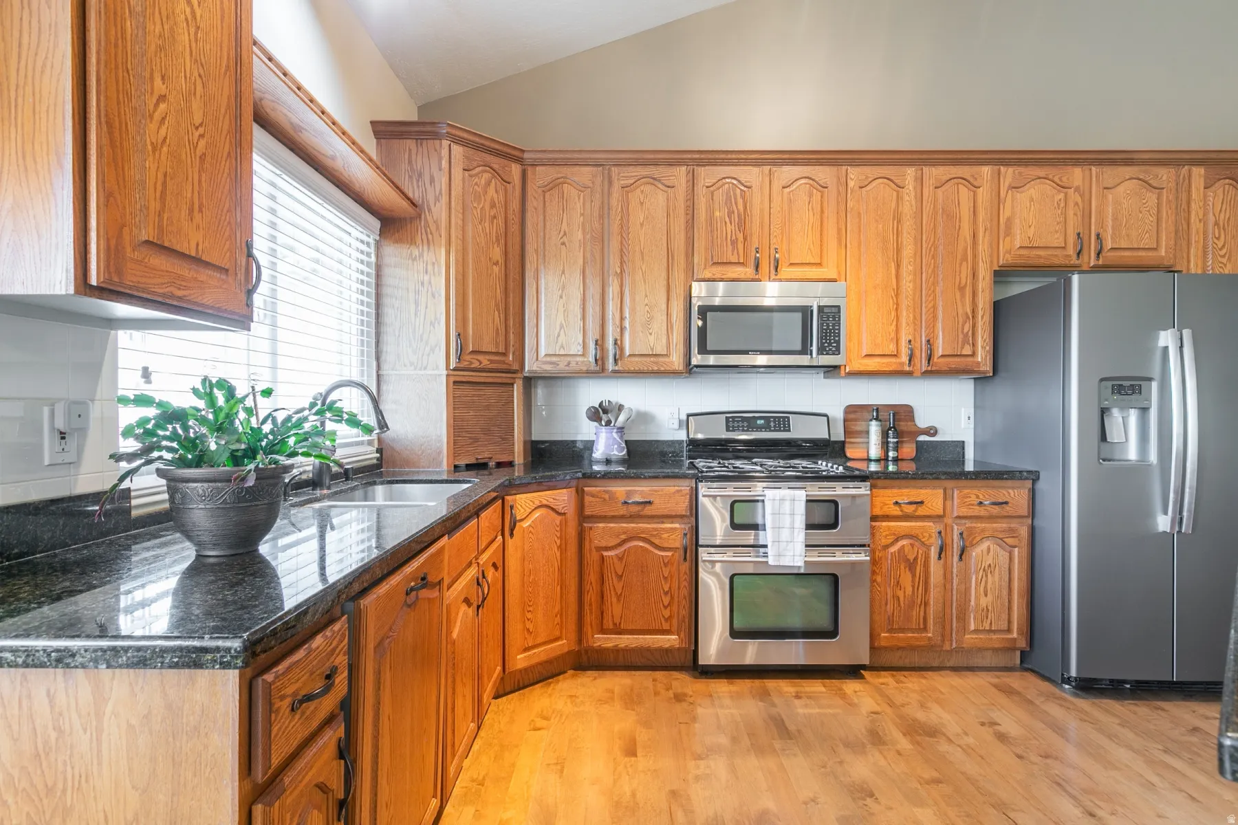 Kitchen featuring wood-finish cabinetry, dark stone countertops, and a stainless steel appliance suite