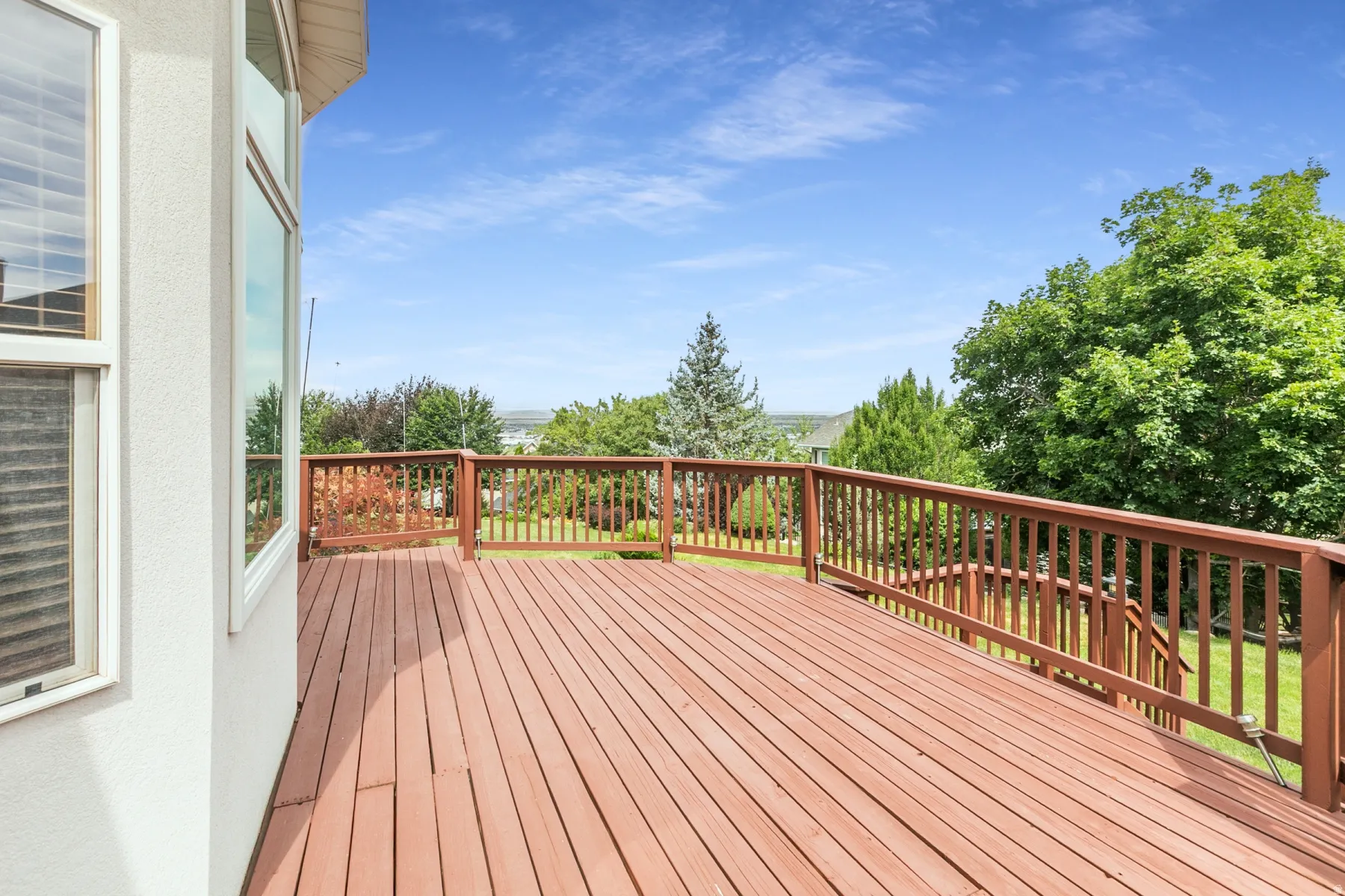 Spacious exterior deck featuring wood-finish decking and a coordinating wood railing