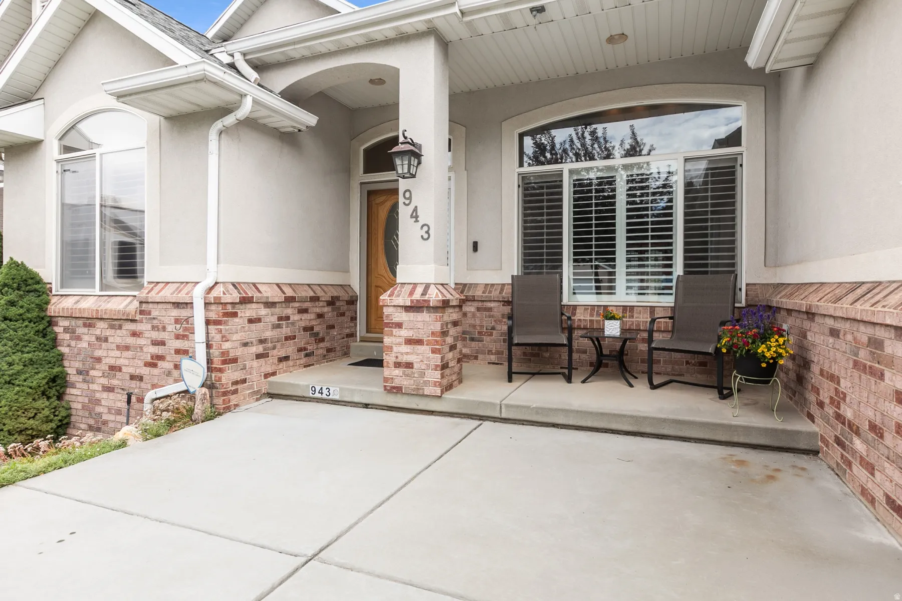 Inviting front entrance featuring a covered porch, brick veneer accents, an arched entryway, and an oval glass-paneled door