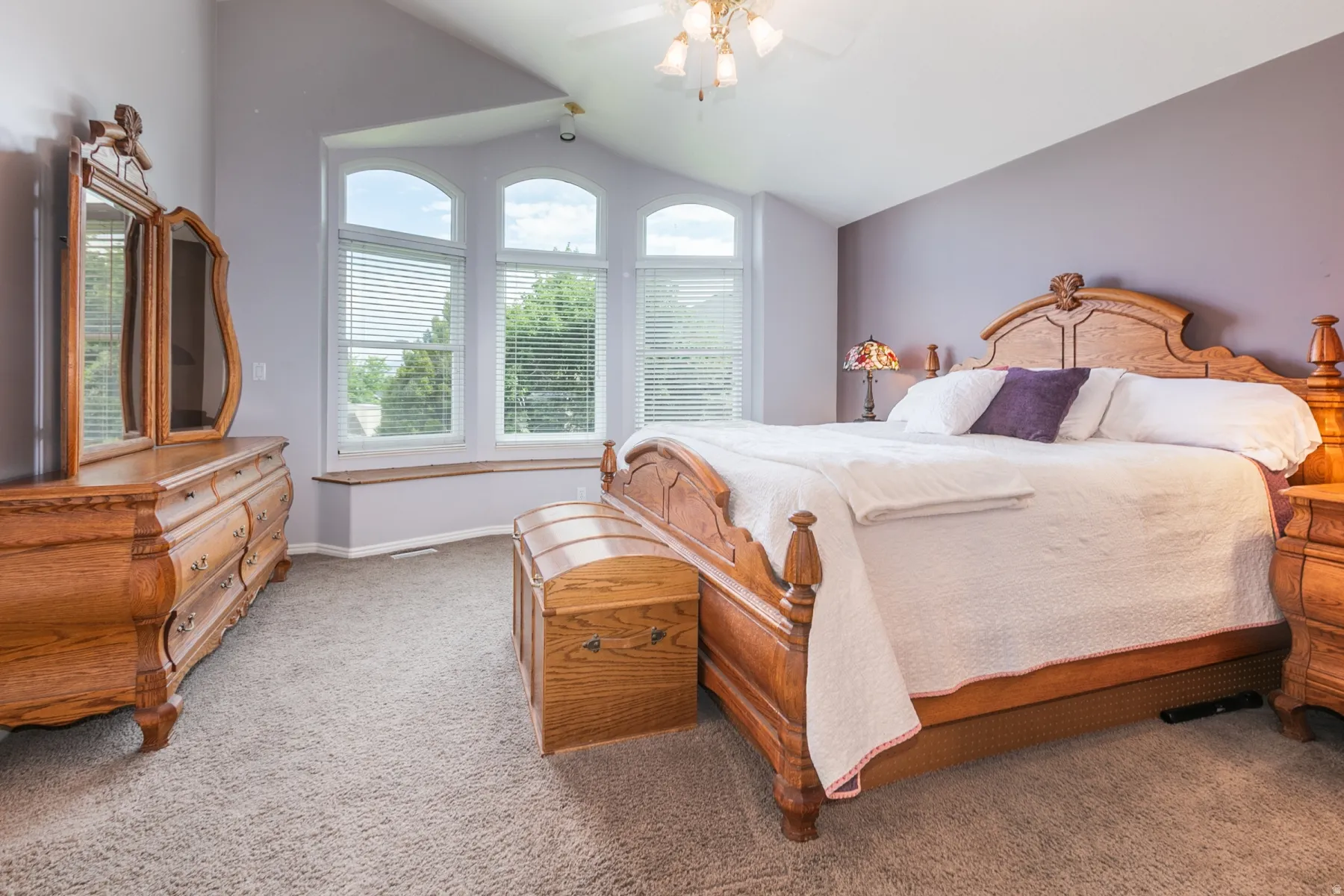 Vaulted ceiling bedroom with arched windows and a built-in window seat