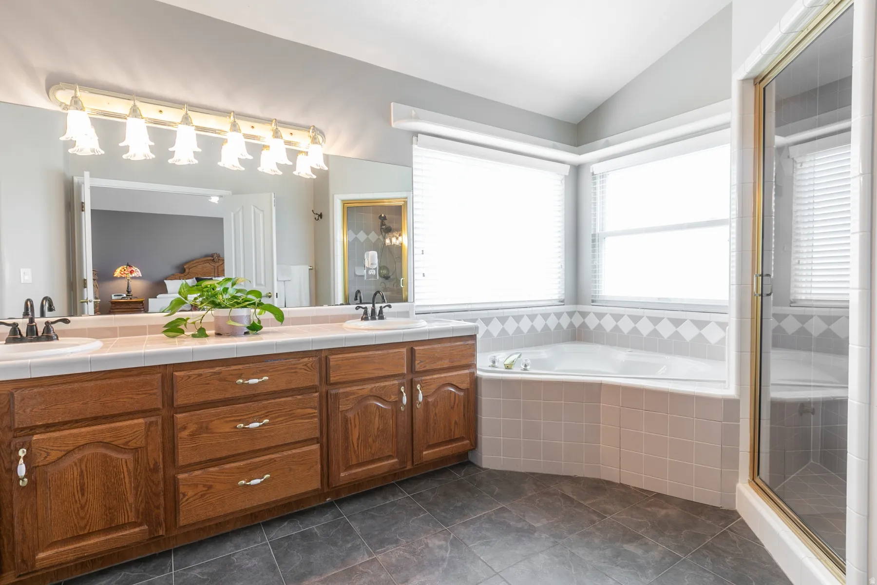 Dual vanity with wood cabinetry, large mirror, and overhead light fixture