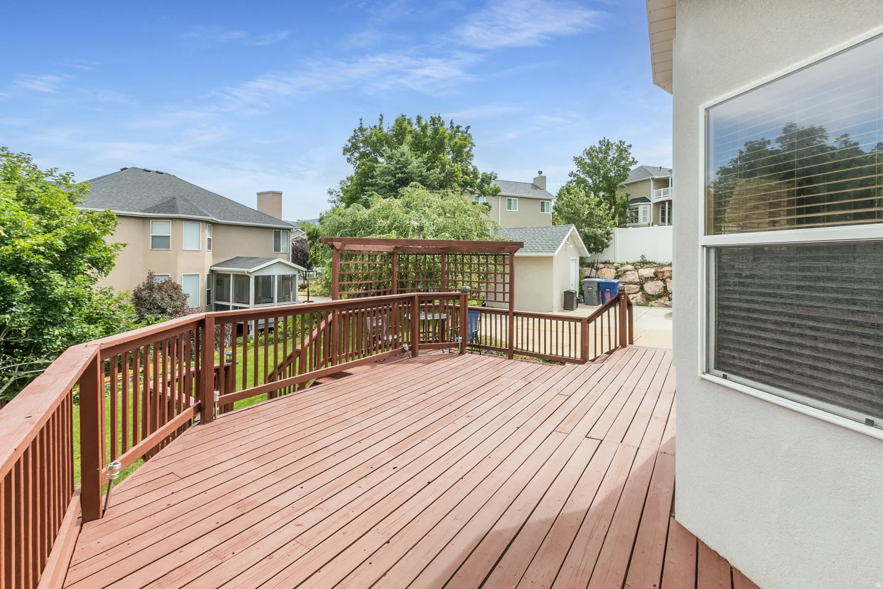 Spacious outdoor wood deck with a matching wood railing and pergola