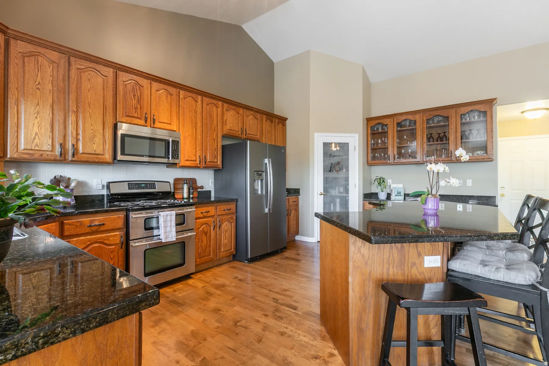 Kitchen featuring wood-finish cabinetry, dark countertops, stainless steel appliances, and wood-finish flooring