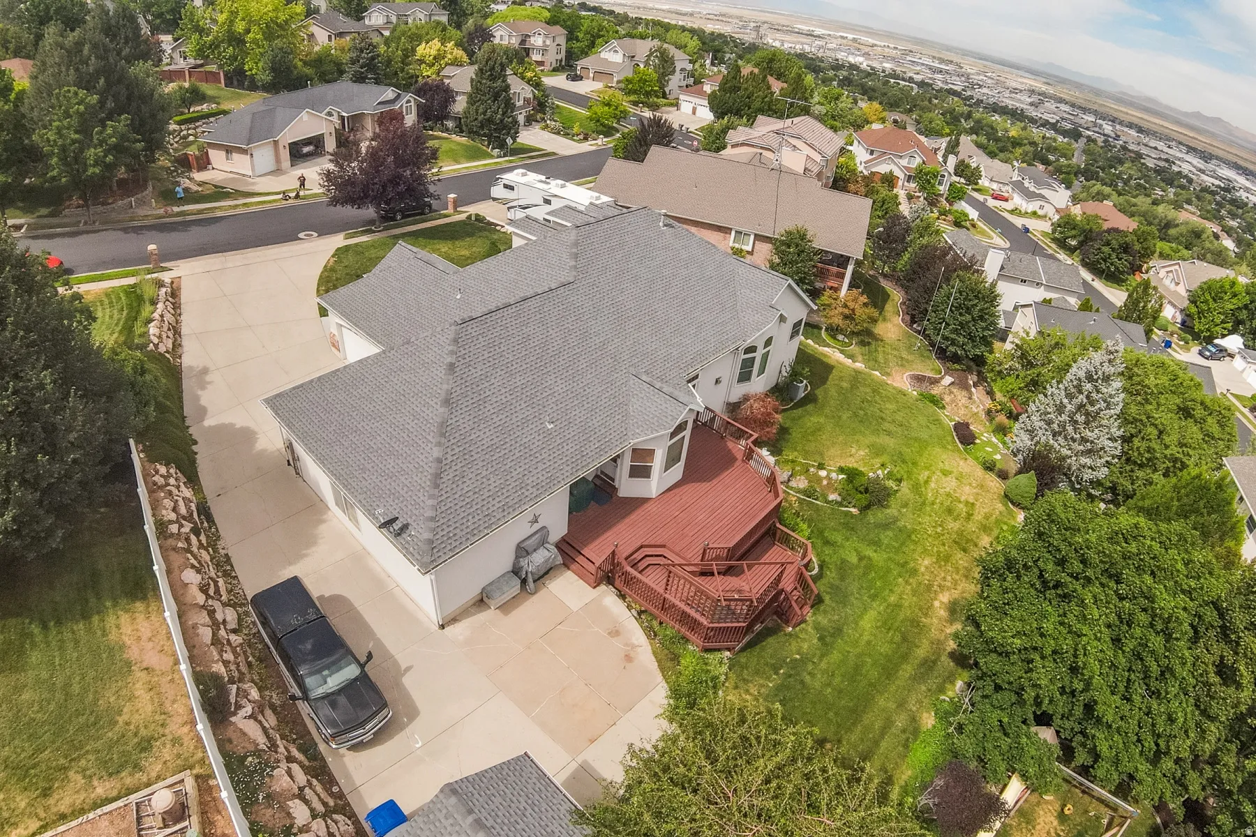 Spacious property featuring a large concrete driveway, two-car garage, and a multi-level wood deck