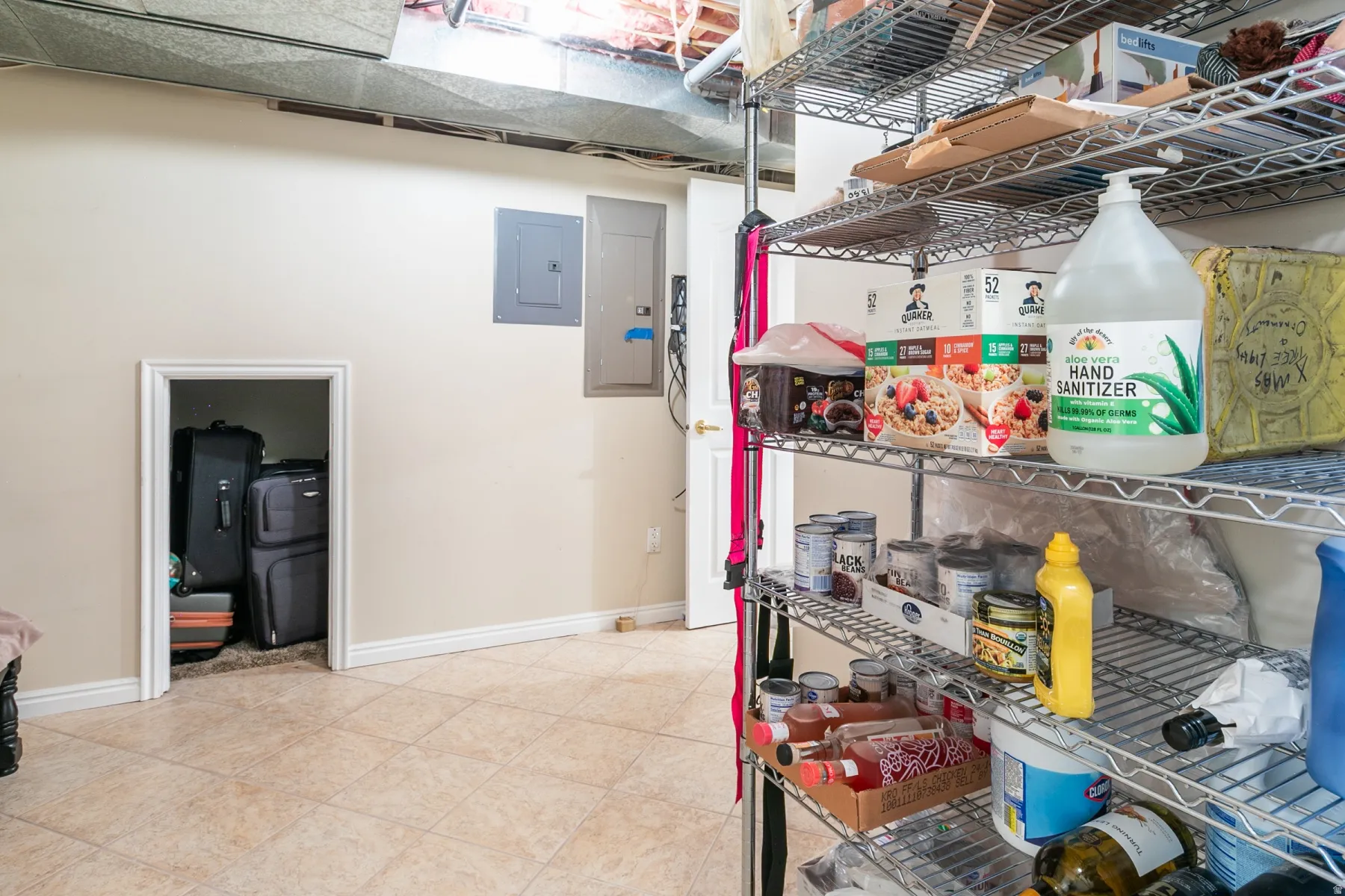 Utility area featuring tiled flooring, a built-in storage alcove, and exposed ductwork