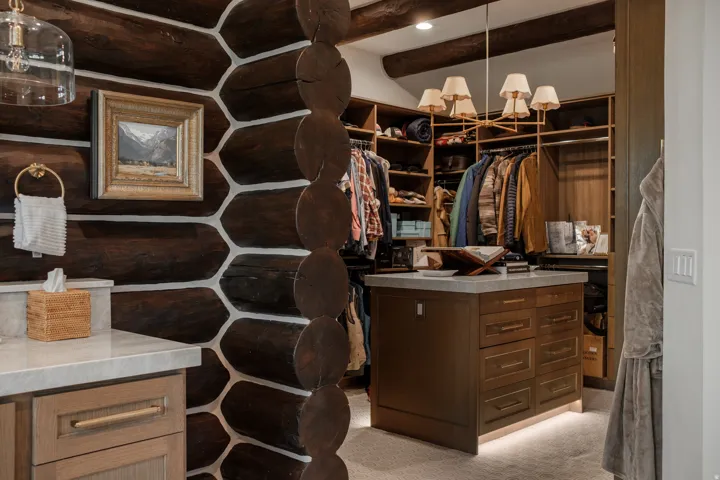 Custom closet featuring a central island with drawers, integrated lighting, and a light-toned countertop