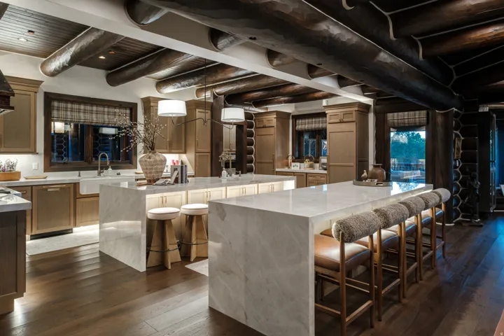 Gourmet kitchen featuring a farmhouse sink, integrated appliances, two waterfall-edge islands, and dark wood-finish flooring