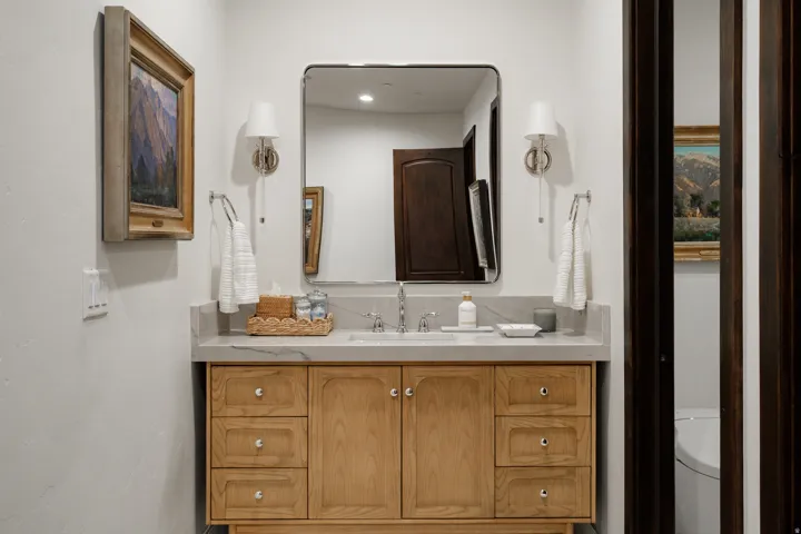 Light wood vanity with integrated sink, stone countertop, and brushed nickel fixtures