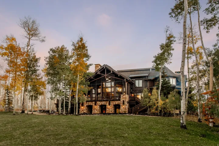 Multi-level log cabin-style exterior with stone accents, extensive windows, and a prominent chimney