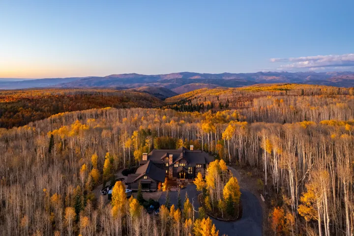 Expansive mountain property with a large residence, surrounded by dense deciduous and evergreen trees