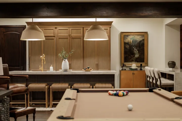 Entertainment space featuring a billiards table, a wet bar with integrated cabinetry and a gold-finish faucet, and a stone countertop