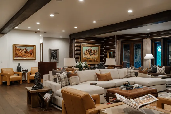 Spacious living area featuring exposed wood beams, recessed lighting, and rich wood-finish flooring