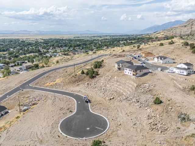 Expansive hillside development featuring newly paved roads, multiple completed residential structures, and various building sites