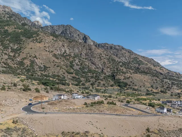 Expansive mountain landscape featuring a development of single-family homes, partially paved roads, and natural terrain