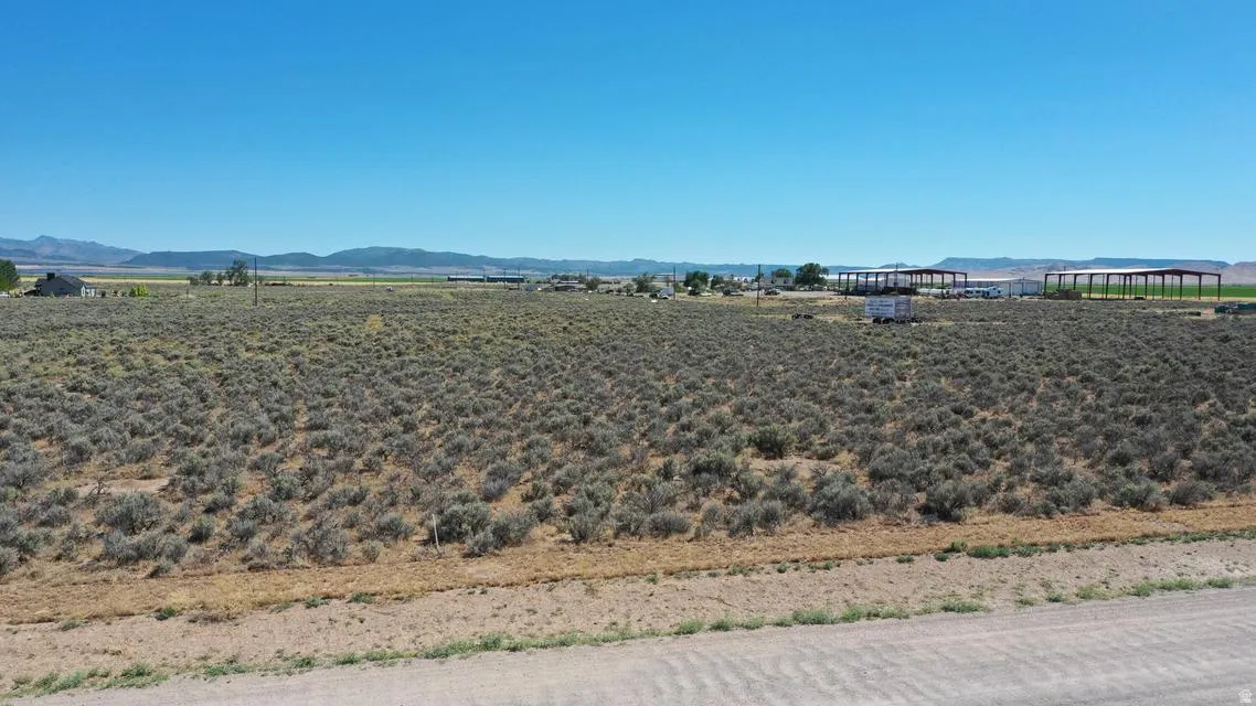 Expansive open land featuring natural vegetation and distant mountain ranges