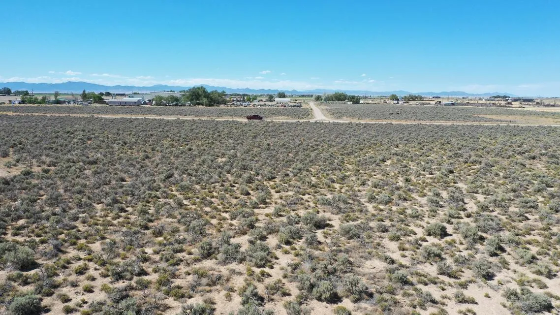 Expansive undeveloped acreage featuring natural scrub brush and distant mountain ranges under a clear sky