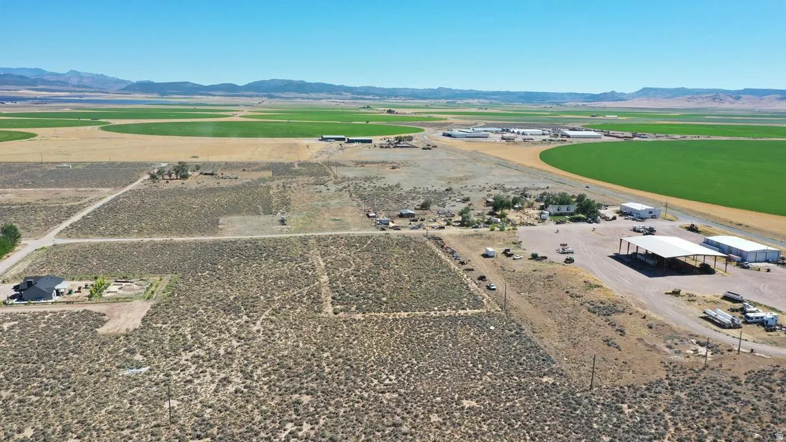 Expansive property featuring vast open land with a distinct building site, a large covered structure, and additional outbuildings