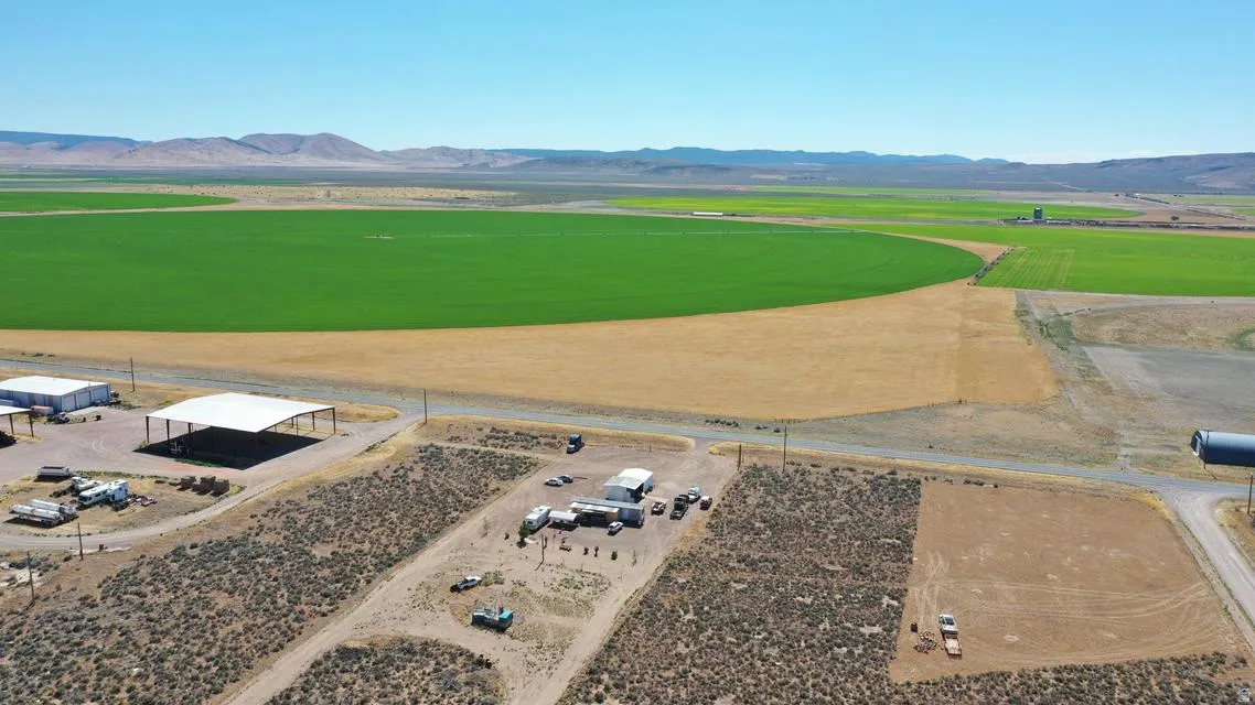 Expansive rural property featuring large agricultural fields, mountainous backdrop, and clear sky