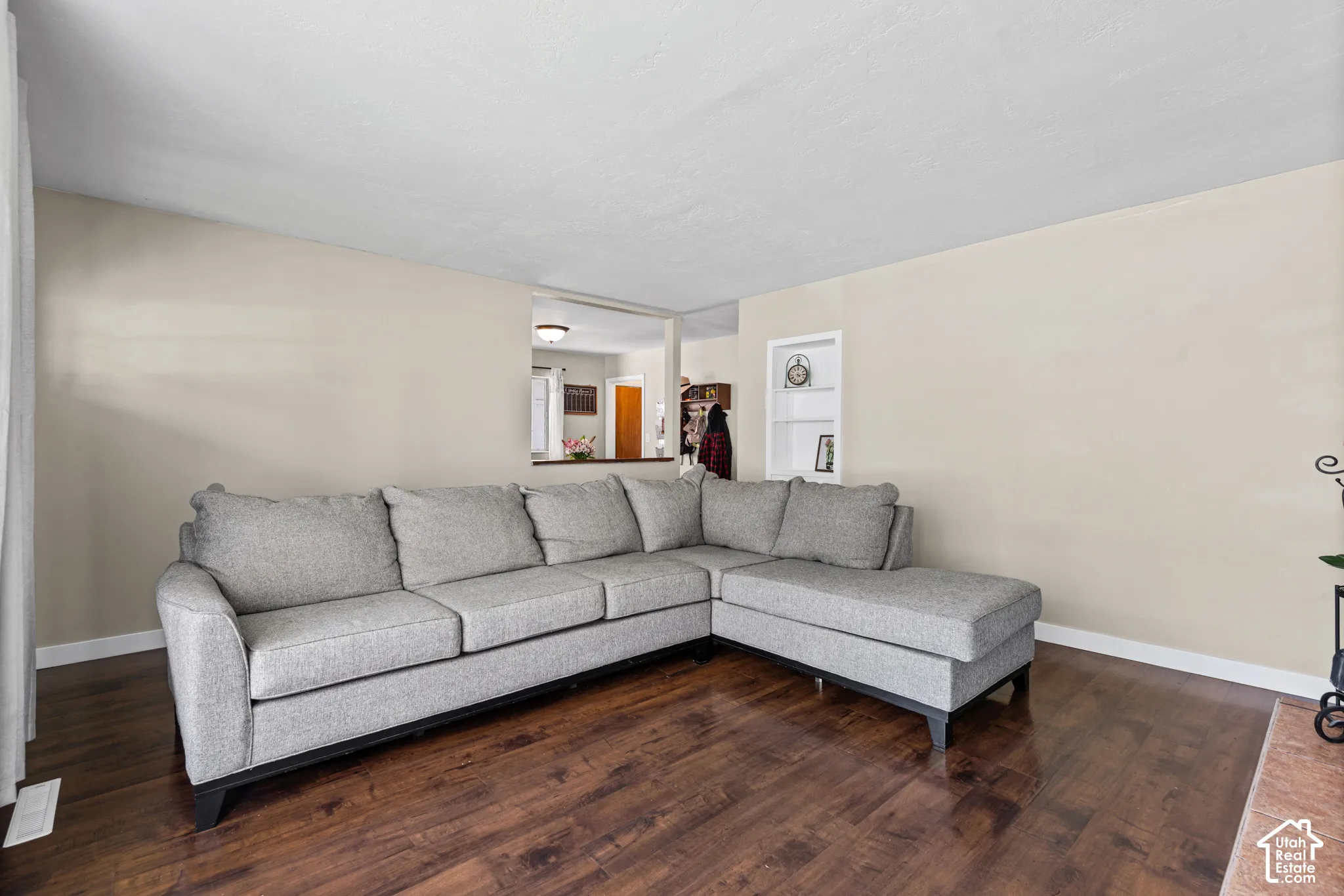 Living area featuring wood-finish flooring, light neutral-toned walls, and a recessed wall shelf