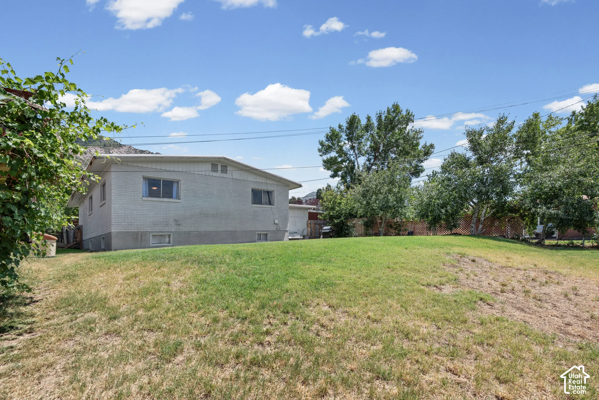Spacious grassy yard with mature trees and a partial mountain backdrop