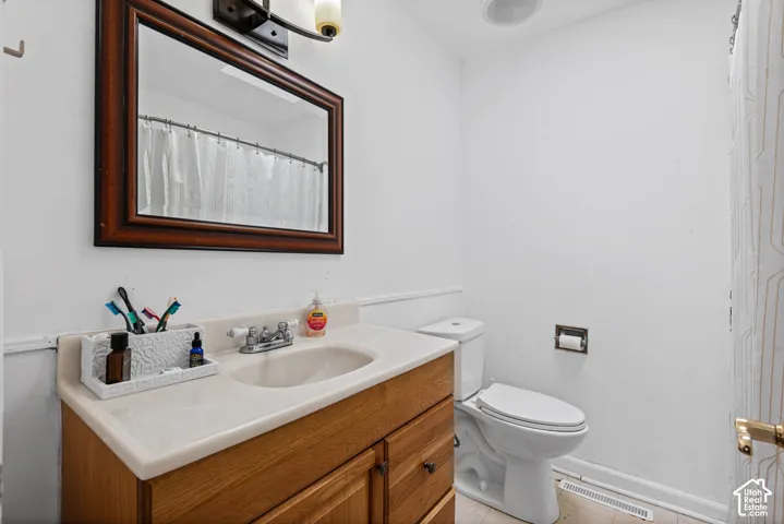 Full bathroom featuring a wood-finish vanity with an integrated sink, a large framed mirror, and white wall paneling
