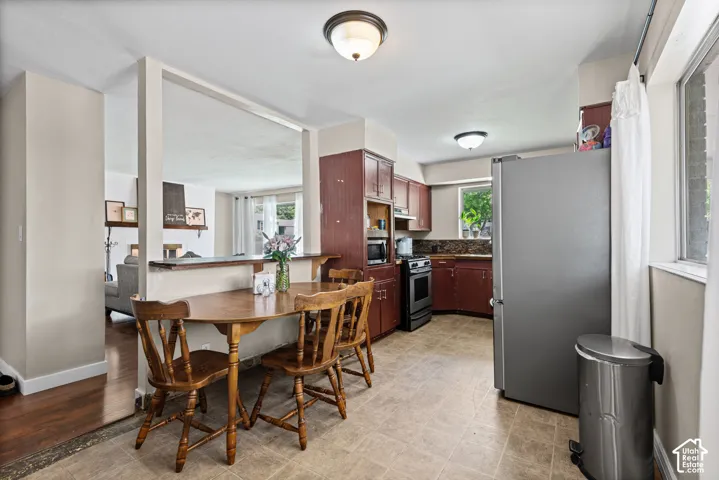 Kitchen and dining area featuring wood-finish cabinetry, tile flooring, and a stainless steel range
