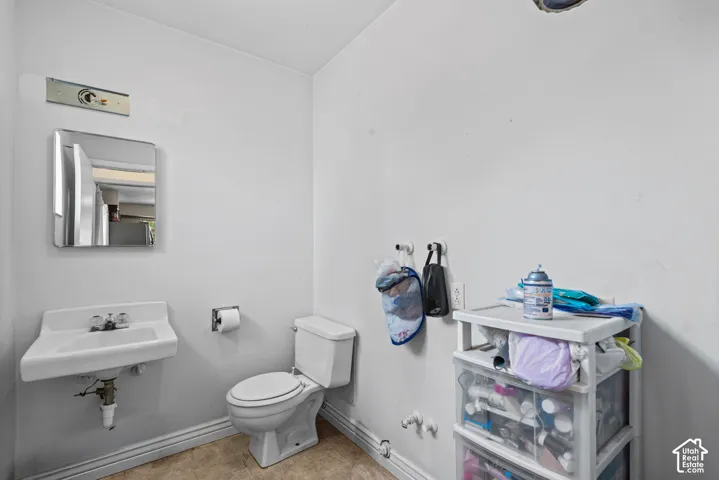 Bathroom featuring a wall-mounted sink, a toilet, a wall-mounted mirror, and neutral wall paint