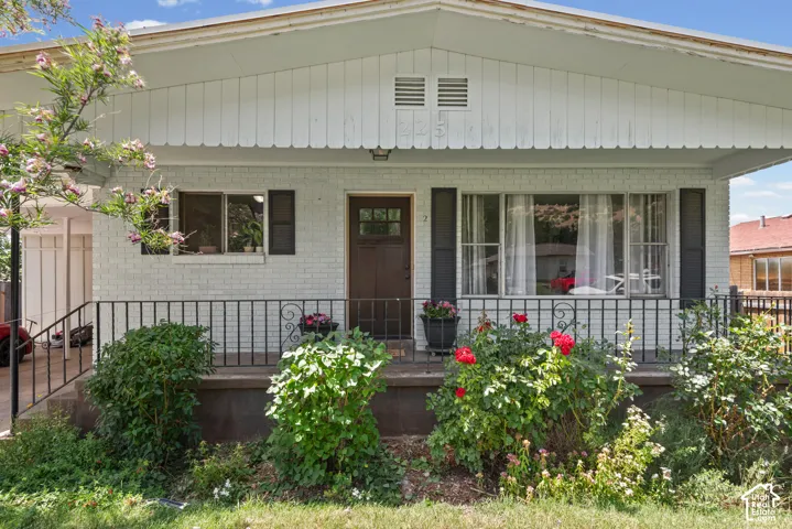 Brick facade with white paint, dark wood entry door, and a covered porch