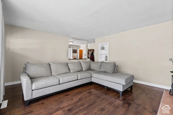 Living area featuring wood-finish flooring, light neutral-toned walls, and a recessed wall shelf
