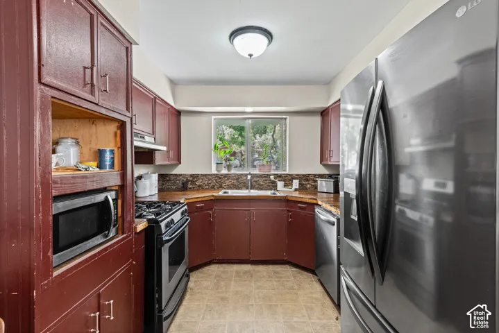 Kitchen featuring abundant cabinetry, a built-in microwave, stainless steel refrigerator, and a gas range