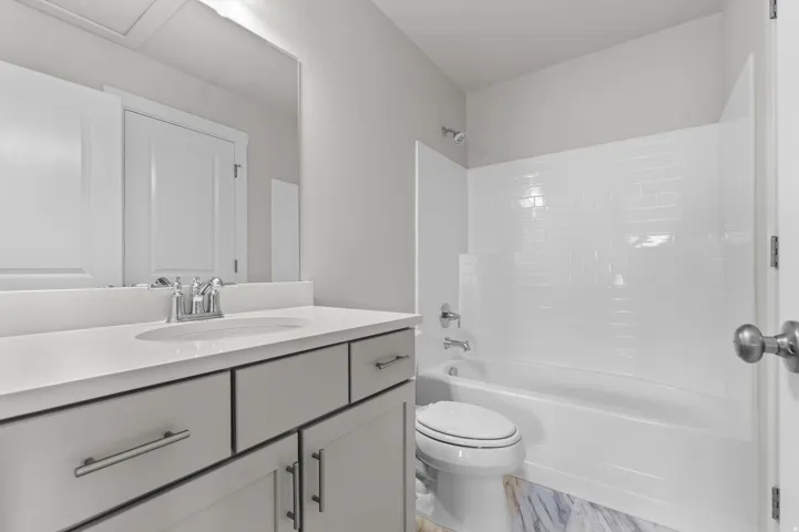 Full bathroom featuring a white vanity with an undermount sink, chrome faucet, and light-toned countertop