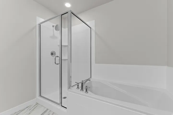 Shower enclosure with chrome fixtures and a separate corner soaking tub with deck-mounted faucet