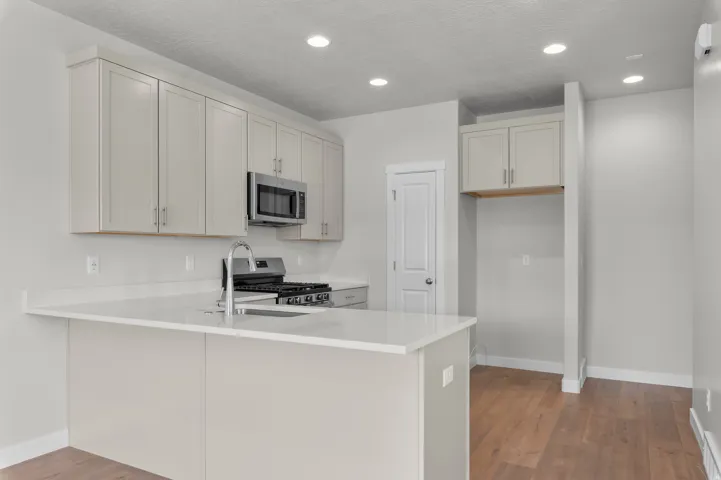 Modern kitchen featuring light-toned cabinetry, stainless steel microwave, and gas range