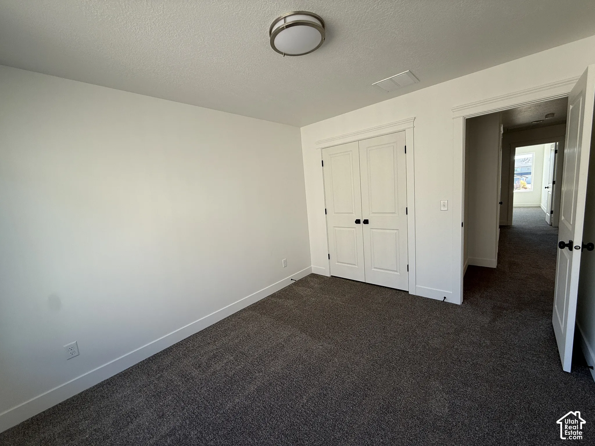 Neutral-toned carpeting, white walls, and a flush-mount ceiling fixture