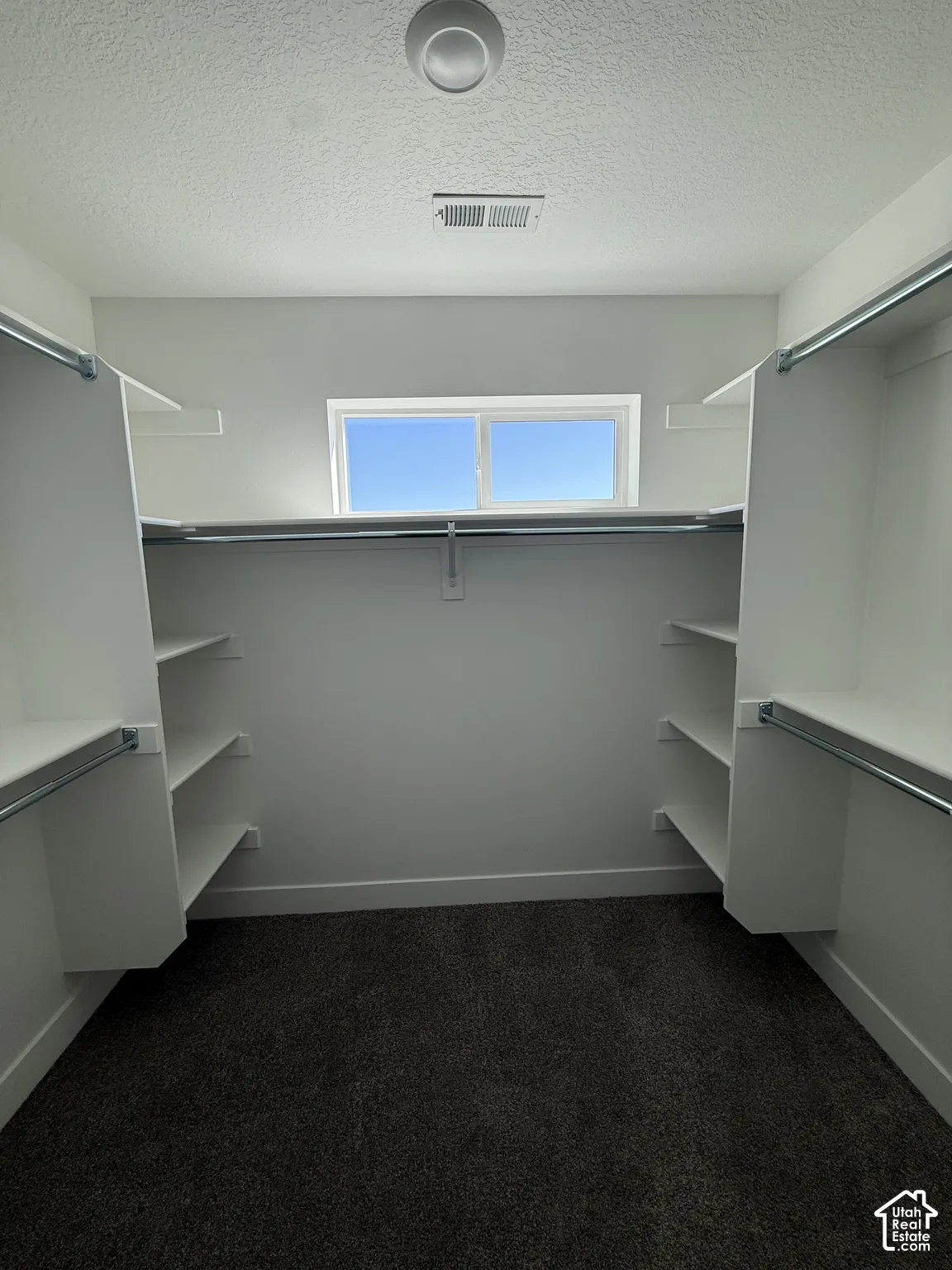 Walk-in closet featuring built-in shelving, hanging rods, and a window for natural illumination