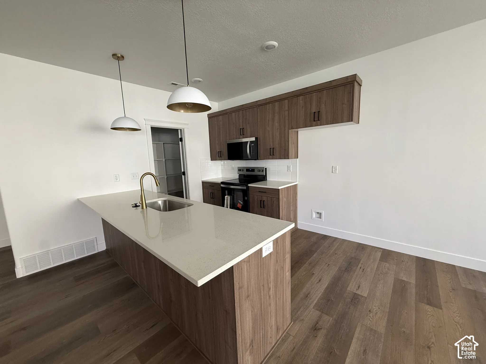 Kitchen featuring wood-finish cabinetry, light-toned countertops, and stainless steel appliances