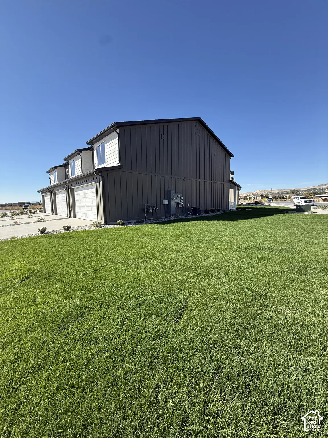 Exterior featuring vertical panel siding, multiple garage bays, and upper-level windows