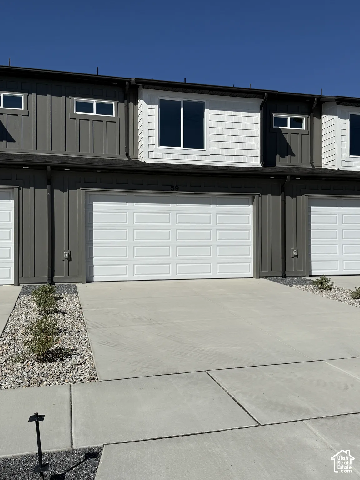 Two-story townhome with a two-car garage, concrete driveway, and board and batten siding