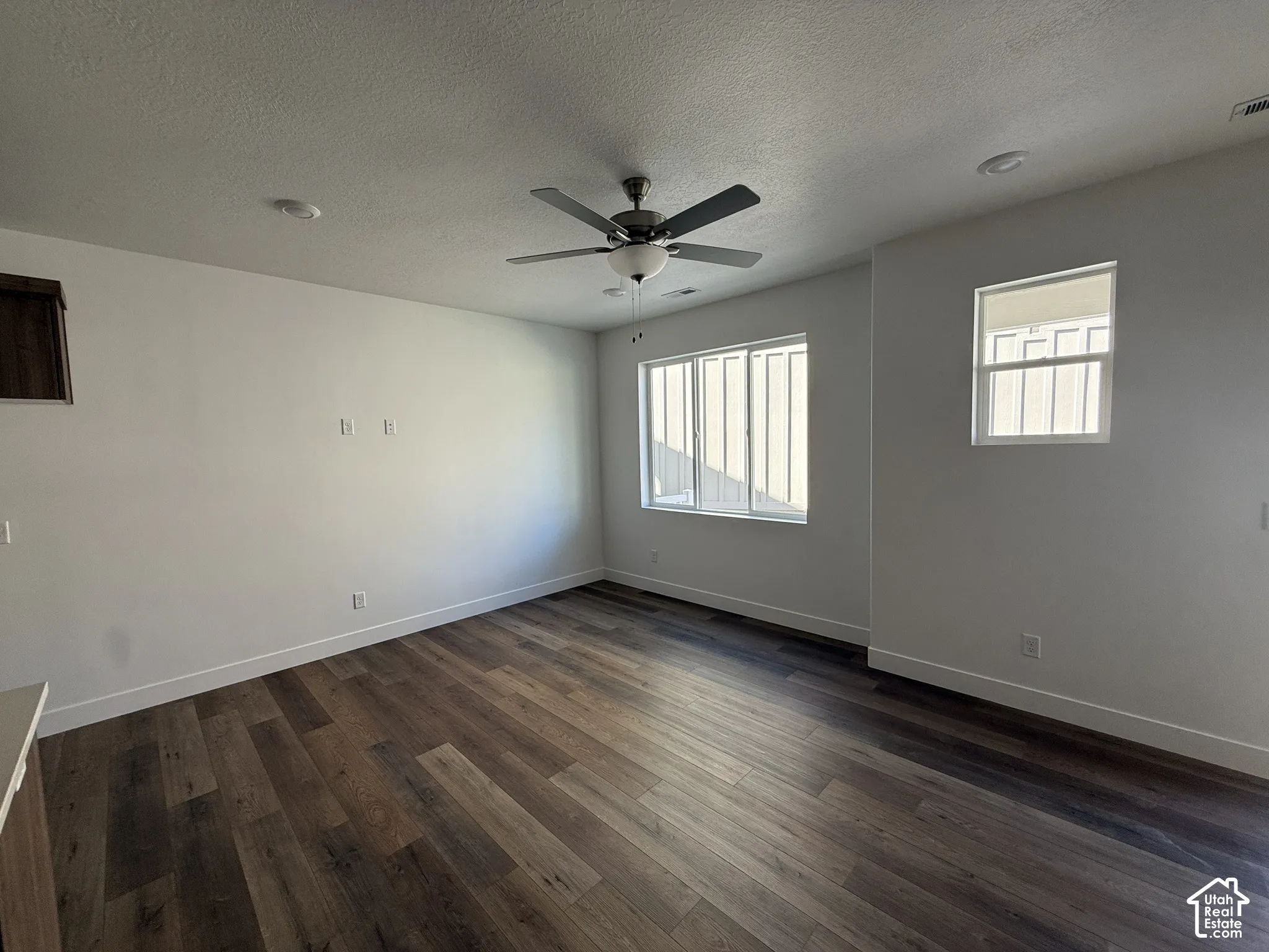 Wood-finish flooring, white walls, multiple windows, recessed lighting, and a ceiling fan
