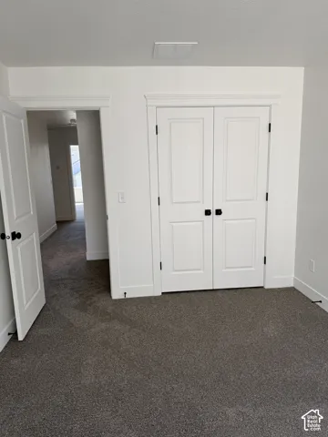 Plush gray carpeting, white trim, white paneled doors with black hardware, and a white ceiling