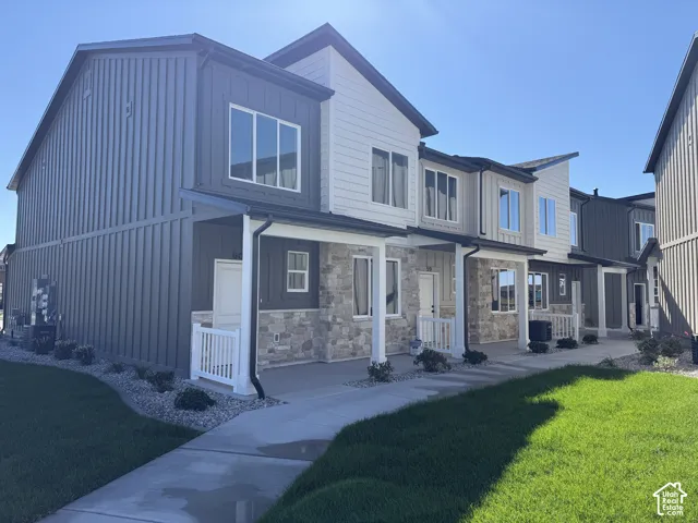 Modern multi-level exterior with vertical siding, stone accents, covered entryways, and white railing details